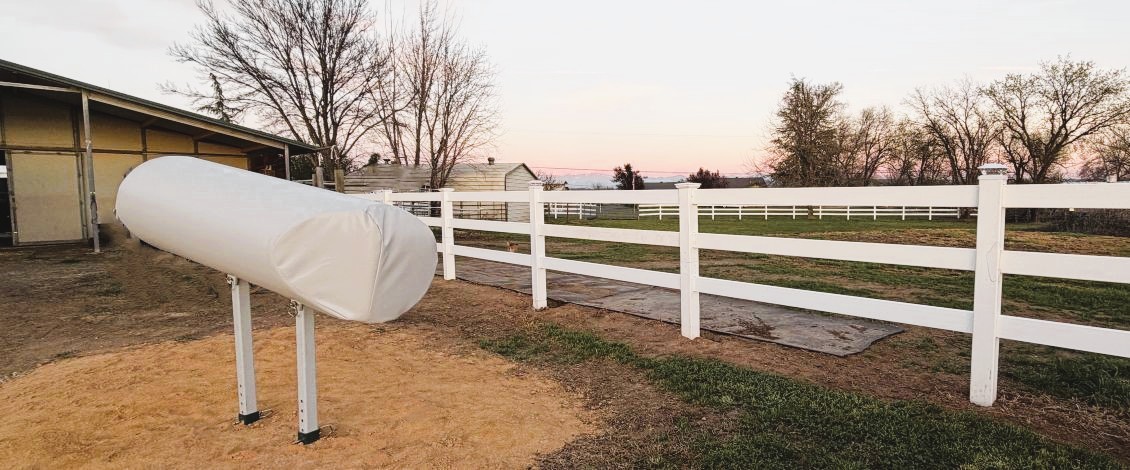 SMS dual-leg stallion breeding phantom mount installed in an outdoor training paddock next to a breeding shed.